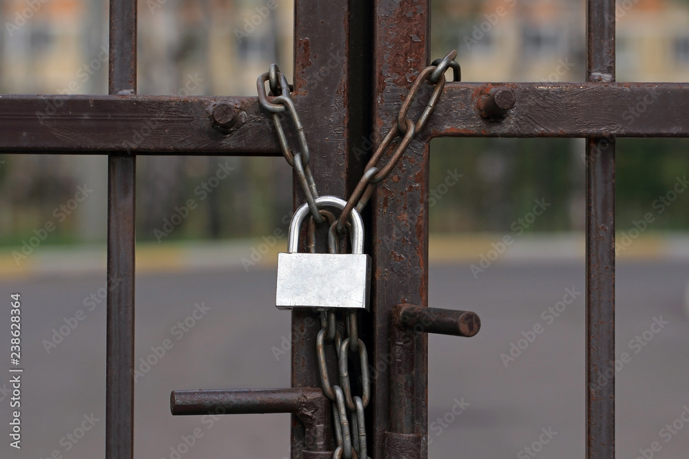 Gate is locked with padlock. Rusted lock on a metal chain. Entrance to prison. Gate is locked with padlock. Rusted lock on a metal chain. Entrance to prison.