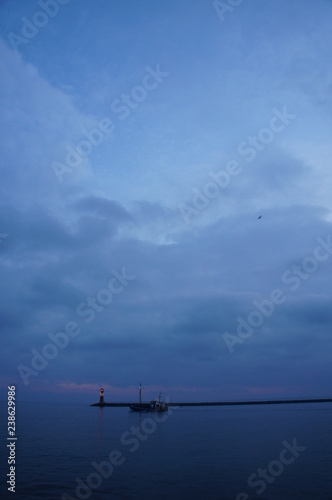 Leuchtturm und Hafeneinfahrt mit Schiffen und Fischerkutter in Warnemünde an der Ostsee im Hafen am Meer