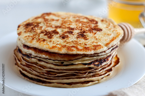 On the table there is a dish with pancakes and honey