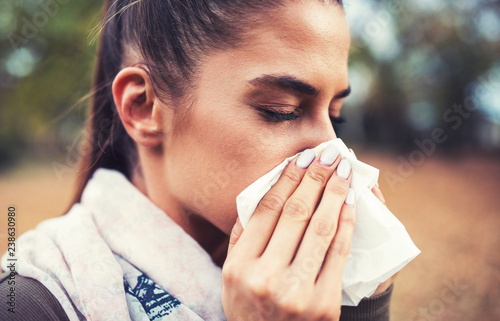 Cold and flu. Woman blowing her nose with a tissue photo