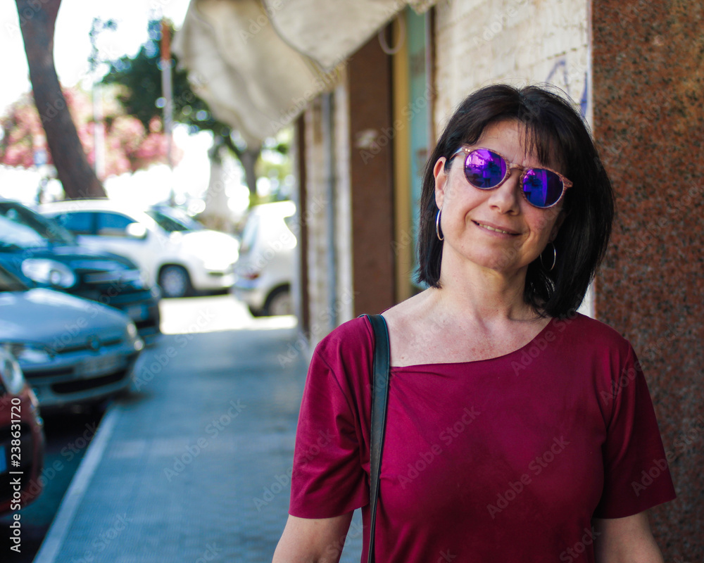 Adult woman with sunglasses smile in front of the camera. Suburban scene Adult woman with sunglasses smile in front of the camera. Suburban scene