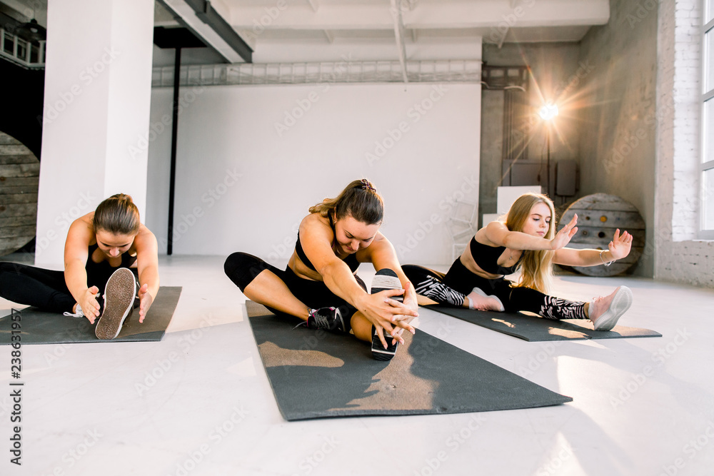 Obraz premium Fitness class and instructor stretching legs in bright exercise room
