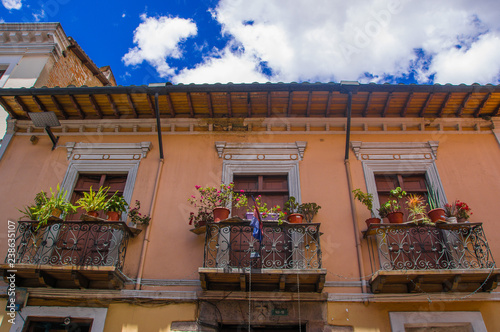 Beautiful colonial building with some flowers and flags hanging from a balcony at historical center of old town Quito in northern Ecuador in the Andes mountains photo