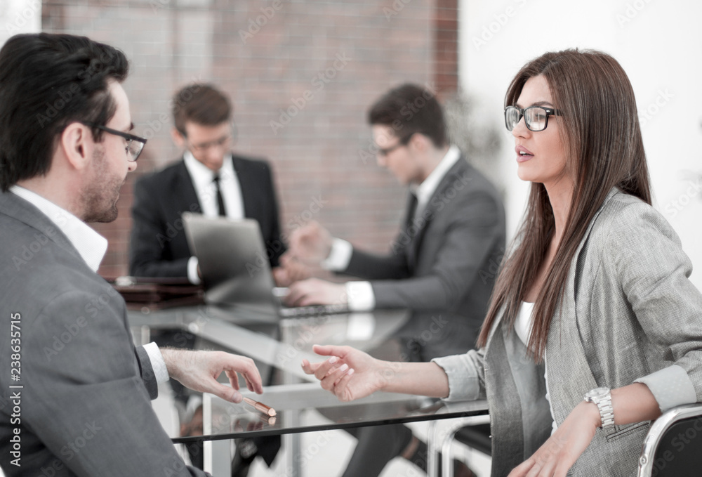 businessman and businesswoman discussing something sitting at office Desk businessman and businesswoman discussing something sitting at office Desk