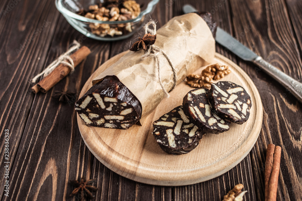 Fototapeta premium Chocolate sachocolate; sausage; background; wooden; baked; biscuit; board; breakfast; brown; butteusage on a wooden background. Dessert made of biscuits, chocolate and nuts is sliced on a wooden board
