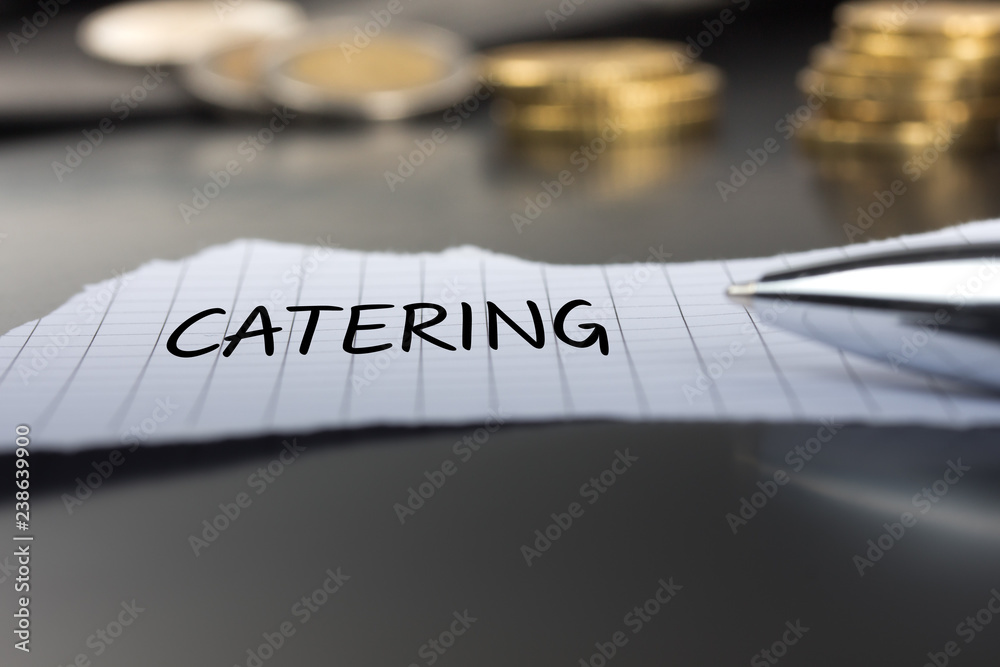 Catering auf einem Zettel mit Stift vor Geldmünzen Catering auf einem Zettel mit Stift vor Geldmünzen
