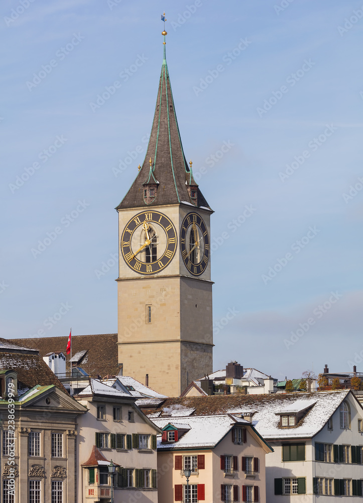 Buildings of the historic part of the city of Zurich along the Limmat river in winter, tower of the St. Peter Church above them