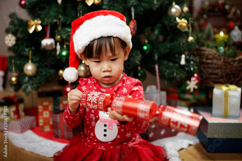 toddler baby girl wearing santa claus costume play in front of christmas tree