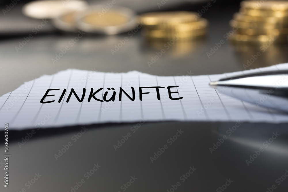 Fototapeta premium Einkünfte auf einem Zettel mit Stift vor Geldmünzen