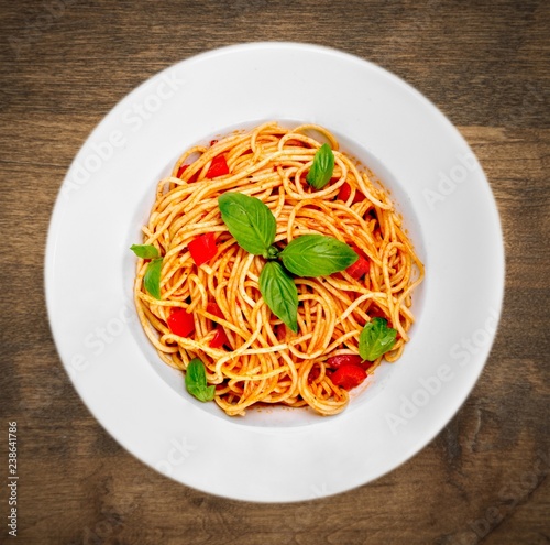 Spaghetti pasta with tomatoes and parsley on table.