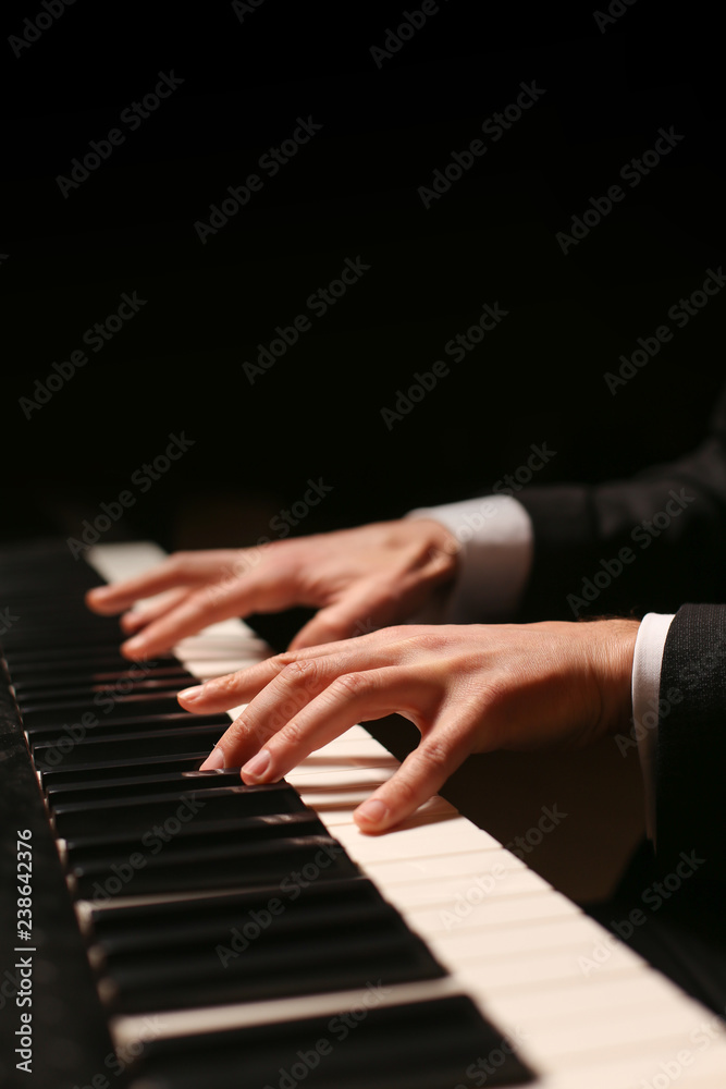 Fototapeta premium Hands on piano. The pianist plays the piano. Piano keys on black background