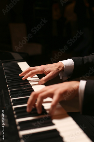 Hands on piano. The pianist plays the piano. Piano keys on black background