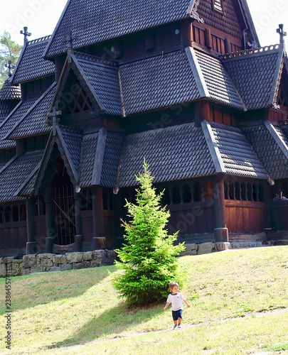 Little two years old boy running and playing in front of the Gol Church,  a stave church originally built in Gol city, but now located in the Norwegian Museum of Cultural History at Bygdoy in Oslo, No photo