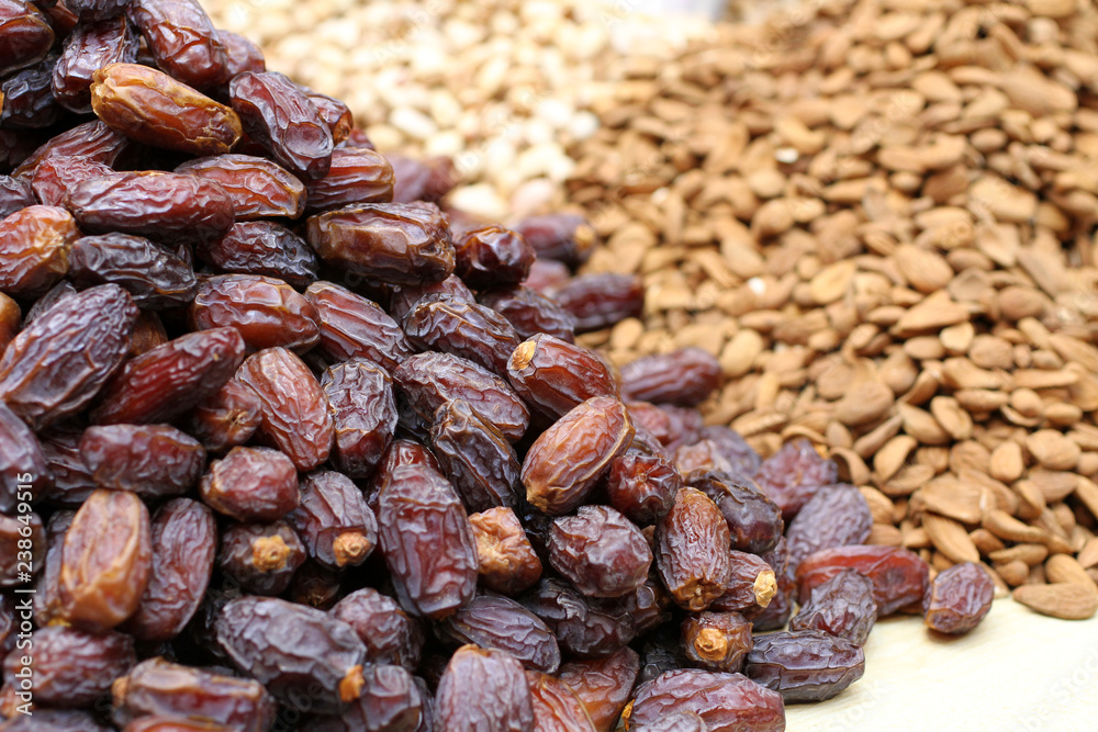 Big dried dates, raw almonds and cashews, lying on a large counter at the market in Deira, Dubai. Big dried dates, raw almonds and cashews, lying on a large counter at the market in Deira, Dubai.