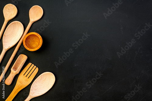 Woodenware set with bowl, spoons and forks on dark background top view mock up