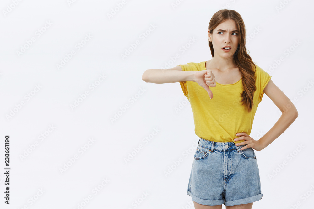 Popular girl dislikes lame try of guy. Bothered displeased and unimpressed arrogant good-looking stylish woman in yellow t-shirt turning eyes left frowning grimacing from dislike showing thumb down Popular girl dislikes lame try of guy. Bothered displeased and unimpressed arrogant good-looking stylish woman in yellow t-shirt turning eyes left frowning grimacing from dislike showing thumb down