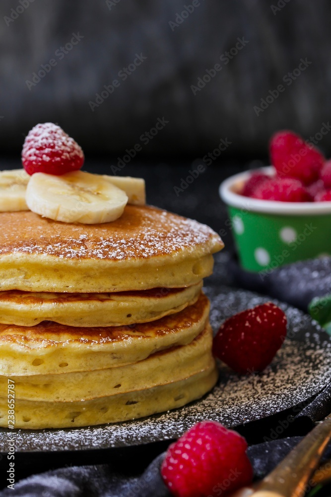 Stack of homemade fluffy pancakes on dark moody background