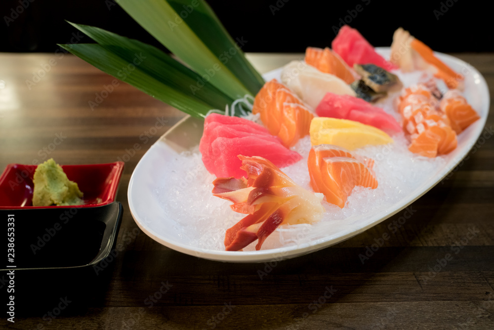 Mixed sliced fish sashimi on ice in white bowl. Sashimi Salmon Tuna Hamachi Prawn and Surf Calm set, raw fish, japanese food in Asian restuarant. Mixed sliced fish sashimi on ice in white bowl. Sashimi Salmon Tuna Hamachi Prawn and Surf Calm set, raw fish, japanese food in Asian restuarant.
