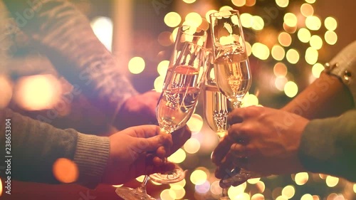 Toasting champagne. Group of people celebrating Christmas party with champagne. Glasses with sparkling wine over glowing background. Slow Motion 4K UHD video footage. 3840X2160 photo