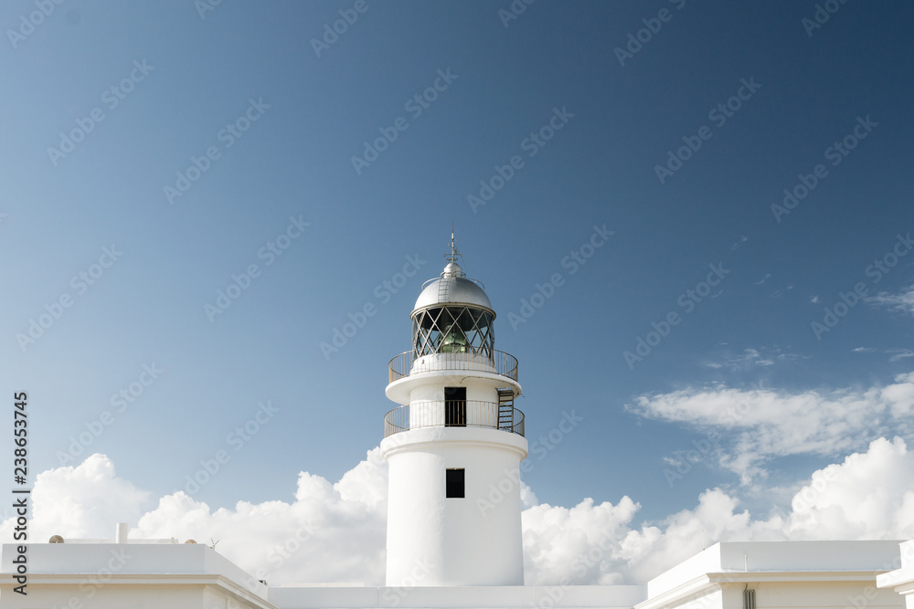 Traditional white light house in a sunny day in Cap Cavallería, Menorca, Balearic Islands, Spain.