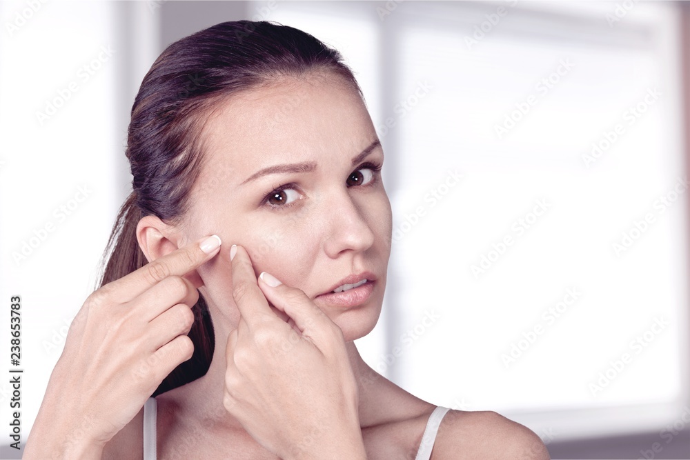 Portrait of young attractive woman touching her face and looking Portrait of young attractive woman touching her face and looking