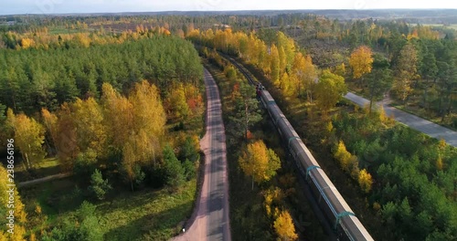 Train in a autumn color landscape, C4K aerial, tracking, drone shot, following a long cargo train, driving on the countryside, on a sunny, fall day, in Uusimaa, Finland