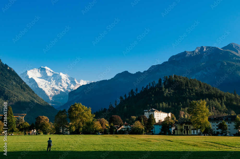 Peolpe in green field Hohematte park and Swiss alps in Interlaken, Switzerland