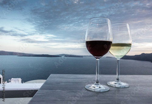 Wine glasses on restaurant table with seascape in background; Santorini island; Greece