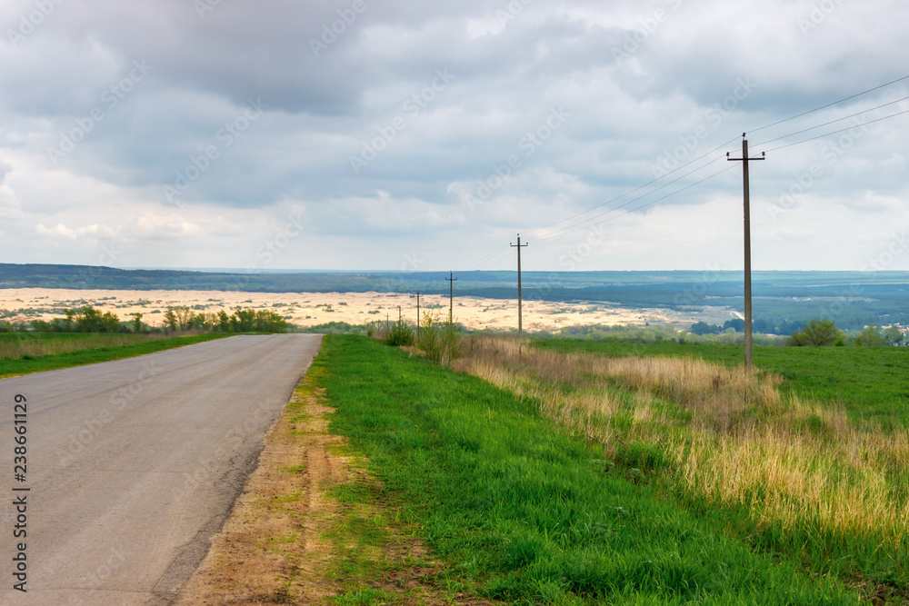 The asphalt rural road leading to the sandy wilderness at the distance The asphalt rural road leading to the sandy wilderness at the distance