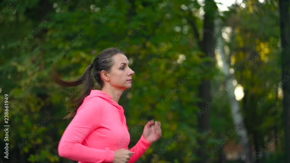 Close up of woman running through an autumn park at sunset. Slow motion Close up of woman running through an autumn park at sunset. Slow motion