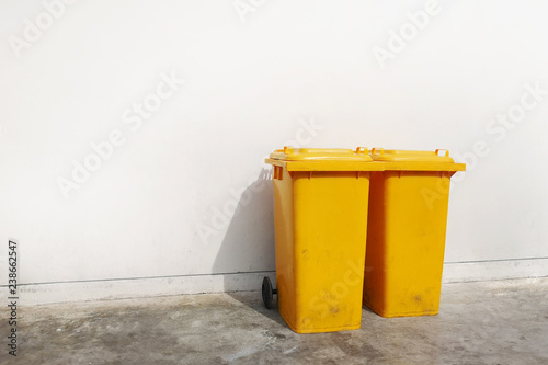 White cement wall background ,There is a yellow bins with a lid. Empty space for text.