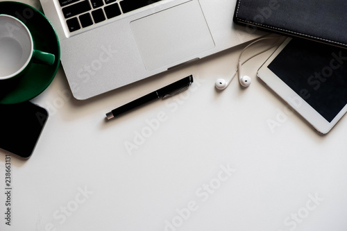 Office supplies are tablet, pen, computer, notebook, mobile phone and red coffee mug placed at an office desk and have a white background.