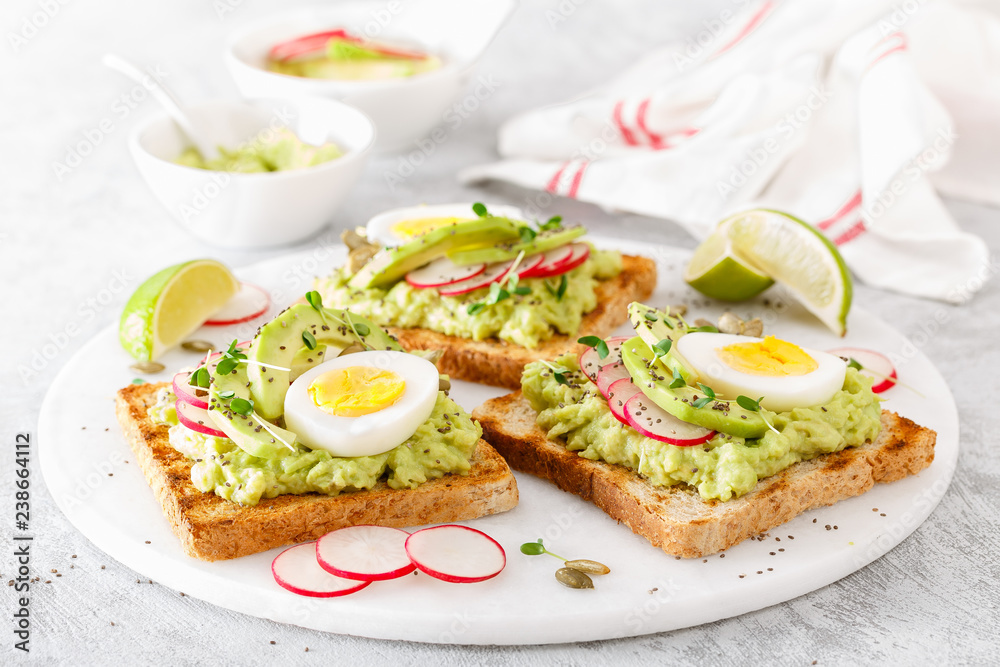 Toasts with avocado guacamole, fresh radish, boiled egg, chia and pumpkin seeds. Diet breakfast. Delicious and healthy plant-based food. Flat lay. Top view