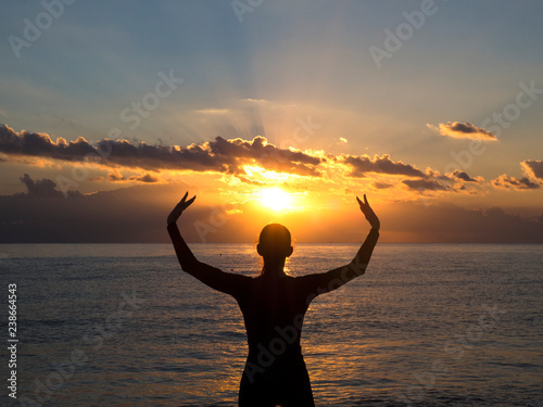 Silhouette woman is play yoga excercise on the beach with sunset or sunrise time