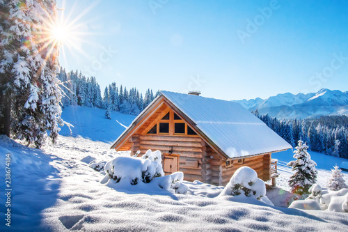 Winter mountain landscape with wooden house on sunny clear day