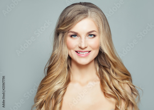 Smiling blonde woman with curly hair and clear skin, fashion portrait