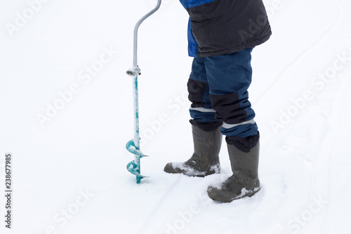 Fisherman makes a hole auger ice screw in winter photo
