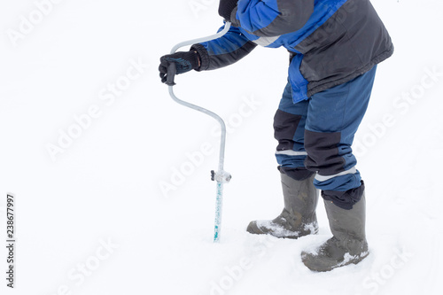 Fisherman makes a hole auger ice screw in winter photo