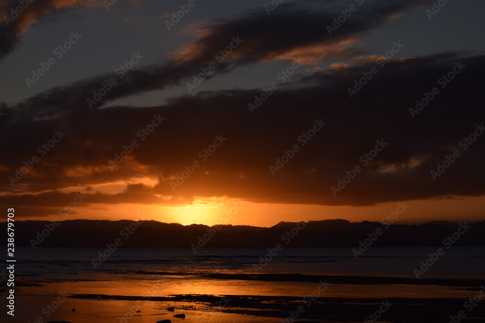 The final glimpse of a orange sunset sandwiched between the night sky and dark hills in Gisborne, New Zealand.
