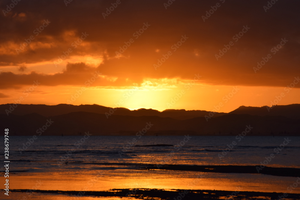 A bright orange sunset sky above the beach landscape in Gisborne, New Zealand.