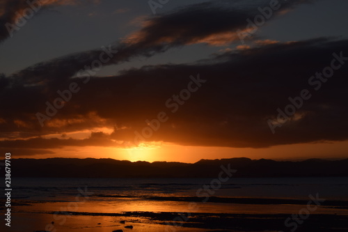 The final glimpse of a orange sunset sandwiched between the night sky and dark hills in Gisborne, New Zealand.