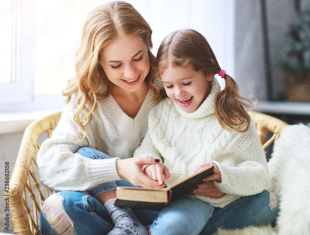 happy family mother reads book to child to daughter by window . happy family mother reads book to child to daughter by window .