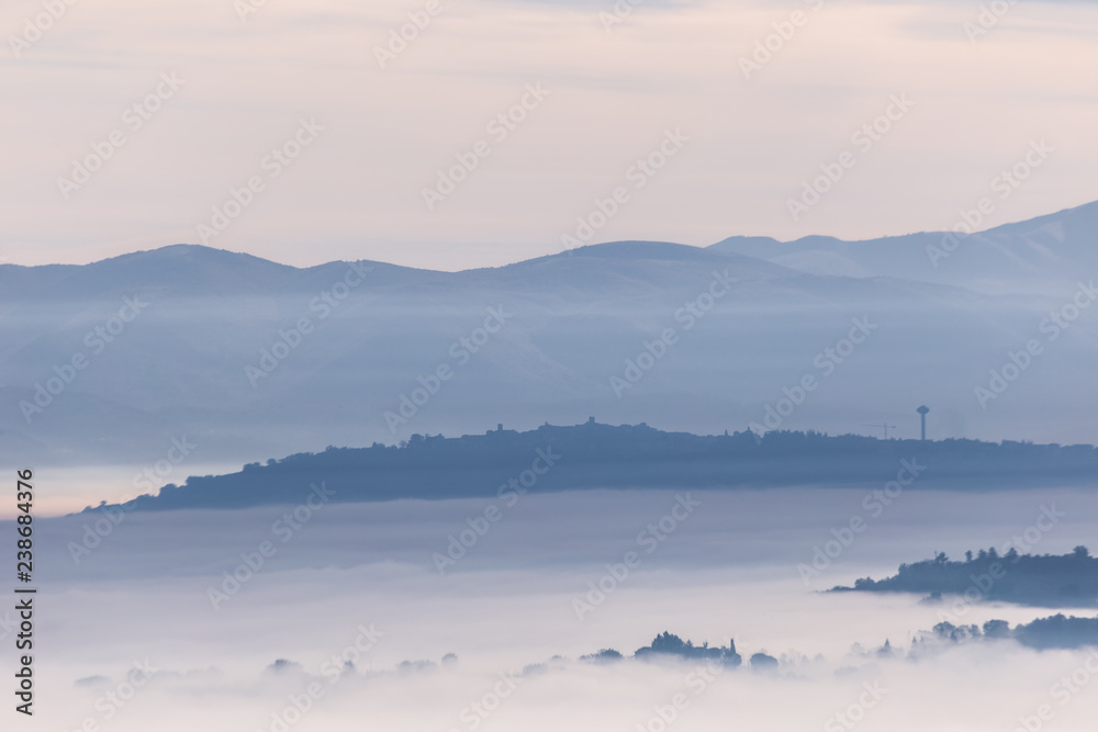 Fog filling a valley in Umbria (Italy), with layers of mountains and hills and various shades of blue Fog filling a valley in Umbria (Italy), with layers of mountains and hills and various shades of blue