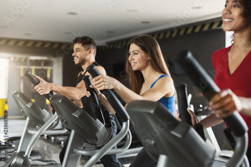 Group of athletes using cross-trainers in sport club