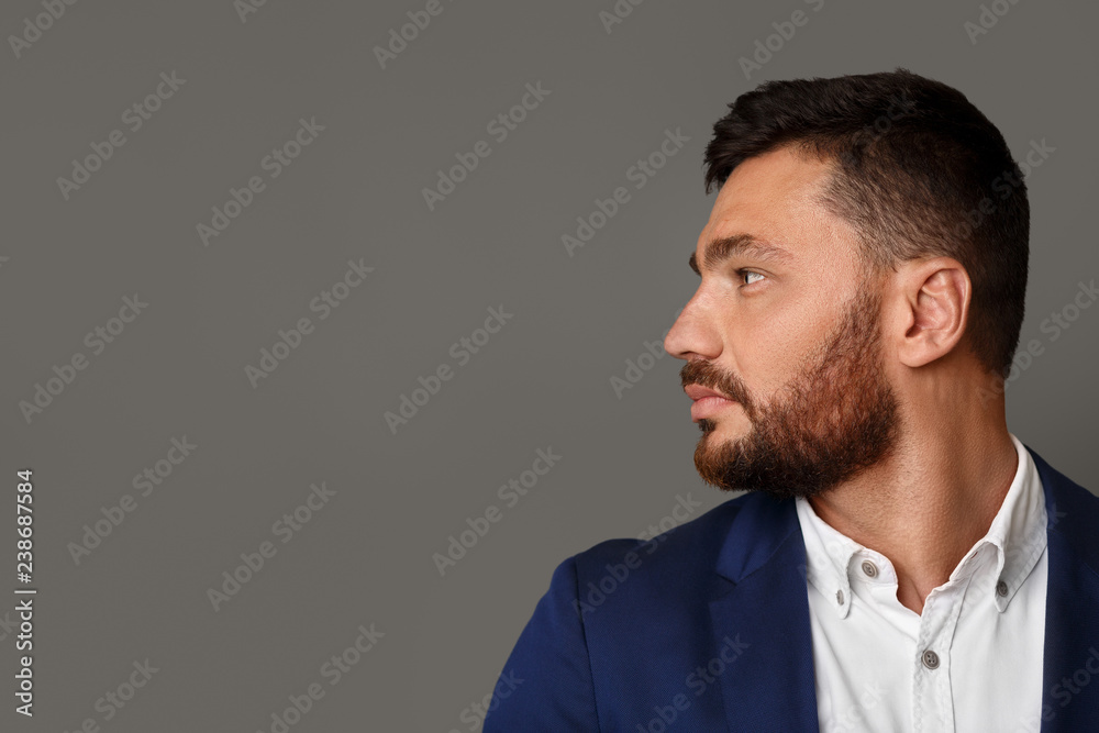 Fototapeta premium Thinking stylish young bearded businessman looking away