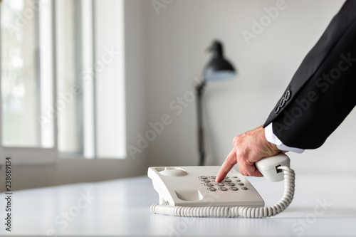 Businessman hand dialing a telephone number