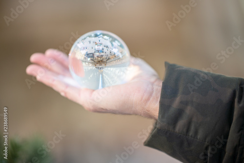 Man’s hand holding large crystal ball with modern station interior reflected in it