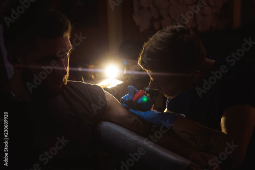 Professional tattoo artist makes a tattoo on a man's hand.