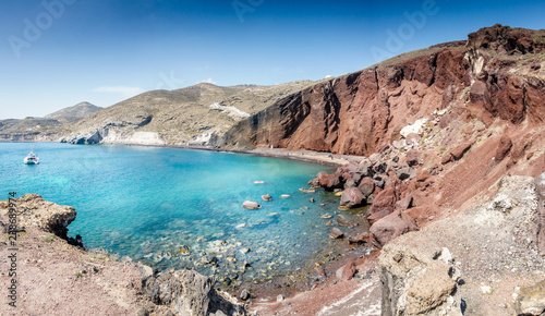 Rocky coastline with boat sailing on Santorini island; Greece