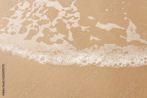 Texture of wet yellow sand with sea wave foam